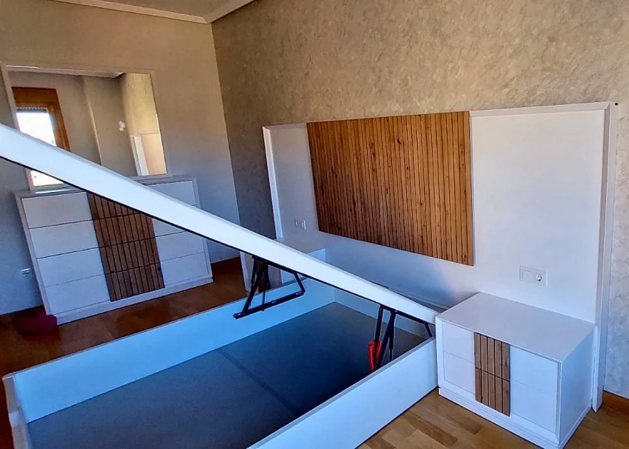 Dormitorio moderno con cama abatible y cabecero en madera alistonada