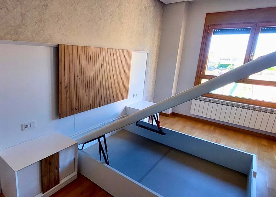 Dormitorio moderno con cama abatible y cabecero en madera alistonada